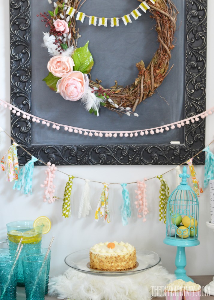 A Fresh & Happy Dessert Table Idea for Spring! A DIY wreath and DIY fabric scrap tassle banner take center stage in this fun aqua, blush pink, moss green and yellow dessert table featuring bird cages, birch candles, feathers and greenery.