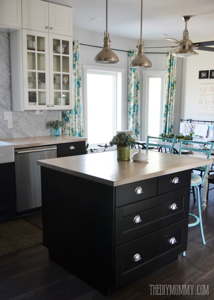 A beautiful vintage industrial kitchen featuring black and white Ikea cabinets, turquoise accents and a Carrara marble stone panel backsplash.