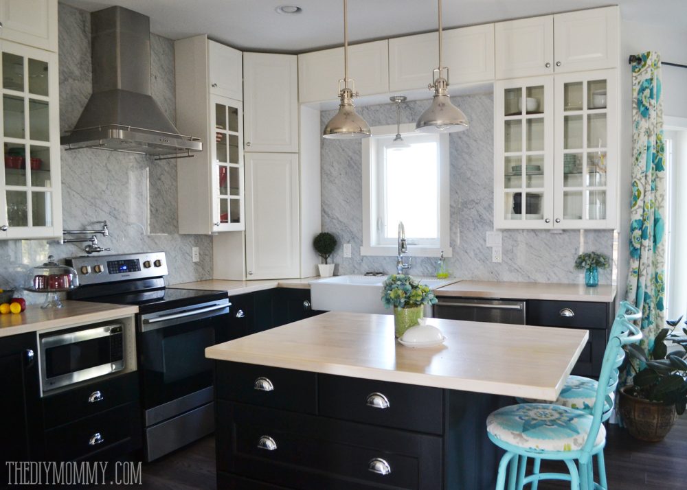 A beautiful vintage industrial kitchen featuring black and white Ikea cabinets, turquoise accents and a Carrara marble stone panel backsplash.