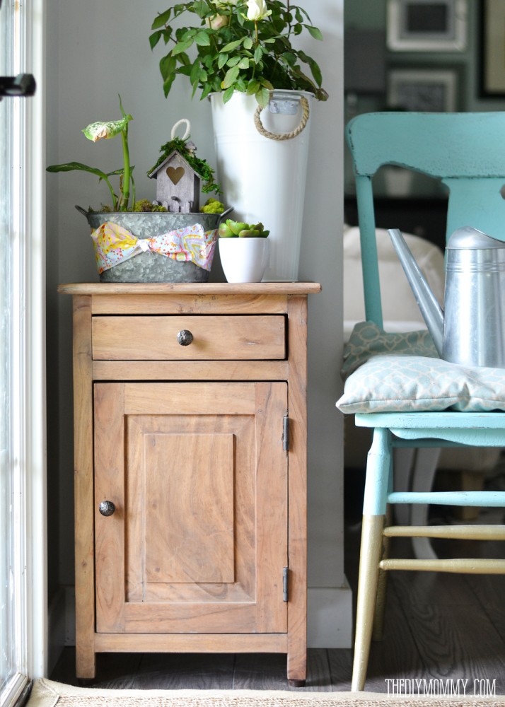 Acacia wood entry cabinet, free map artwork and a turquoise and gold dipped chair at entry