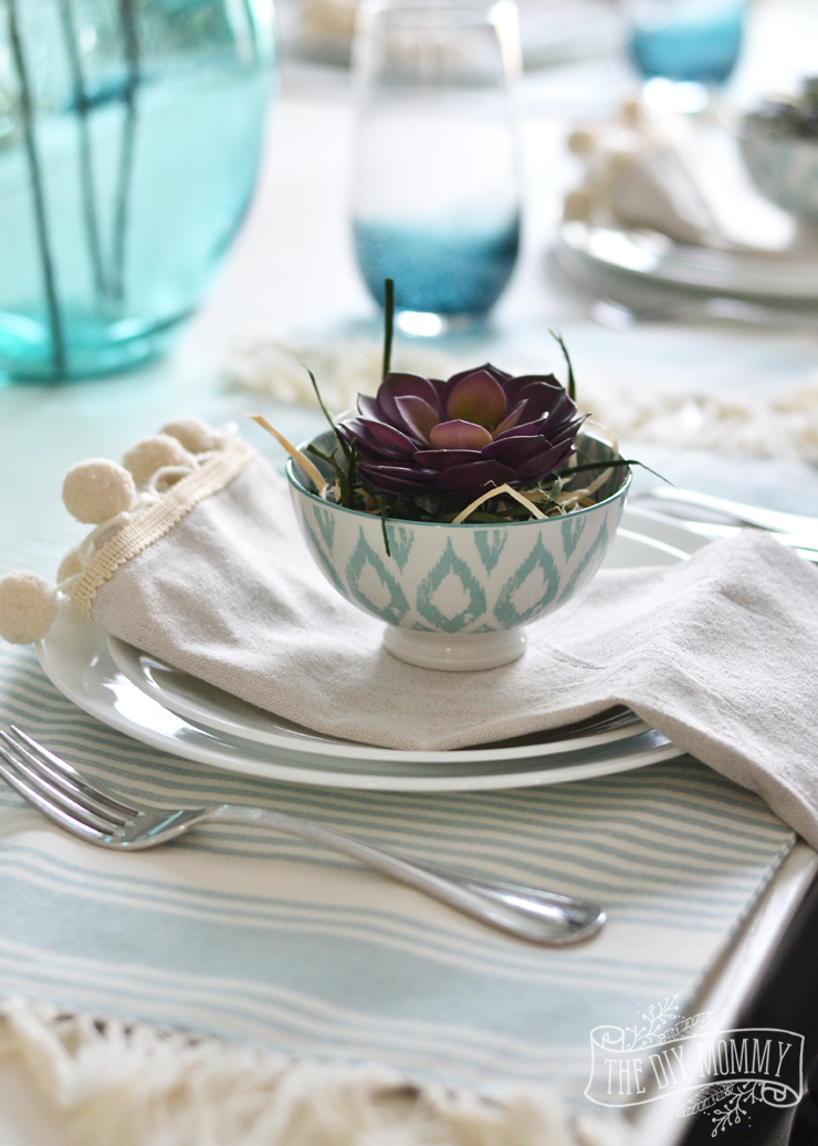 Aqua glassware and succulents are used in this tablescape.