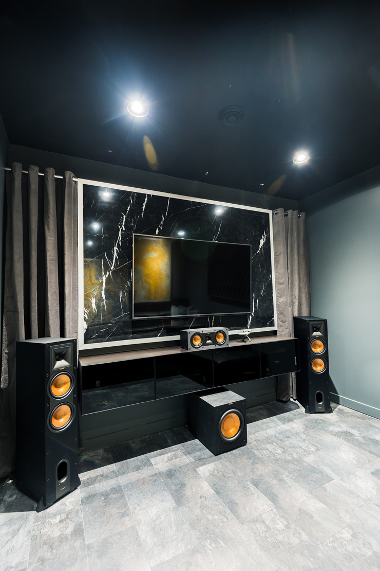 An ultra modern theater room / movie room / man cave design with marble panel artwork in black, grey and rust orange
