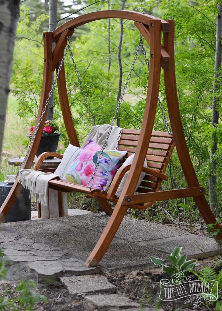 A secret garden swing retreat - the perfect little mini patio in the woods with a shade garden, a wooden swing, and a side table for drinks