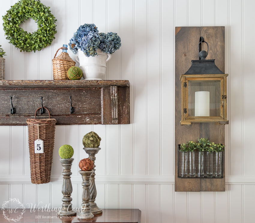 Fixer-Upper-style-diy-hanging-lantern-on-a-wood-plaque-with-a-wire-basked-and-greenery-filled-vases