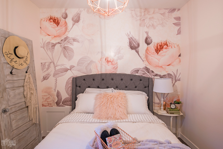 Relooking féminin moderne de la chambre d'amis de la ferme avec une grande fresque murale florale, une tête de lit rembourrée et des couleurs rose pâle, gris et cuivre