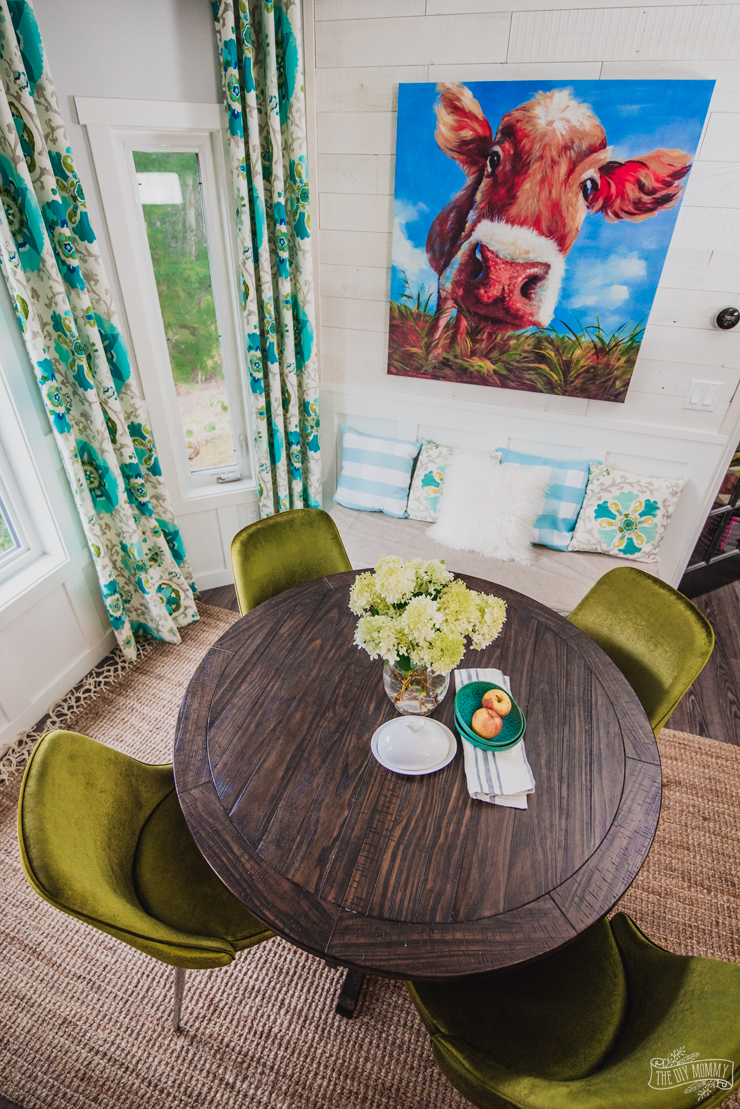 Colorful kitchen breakfast nook featuring a farmhouse table, turquoise drapes and velvet midcentury modern chairs