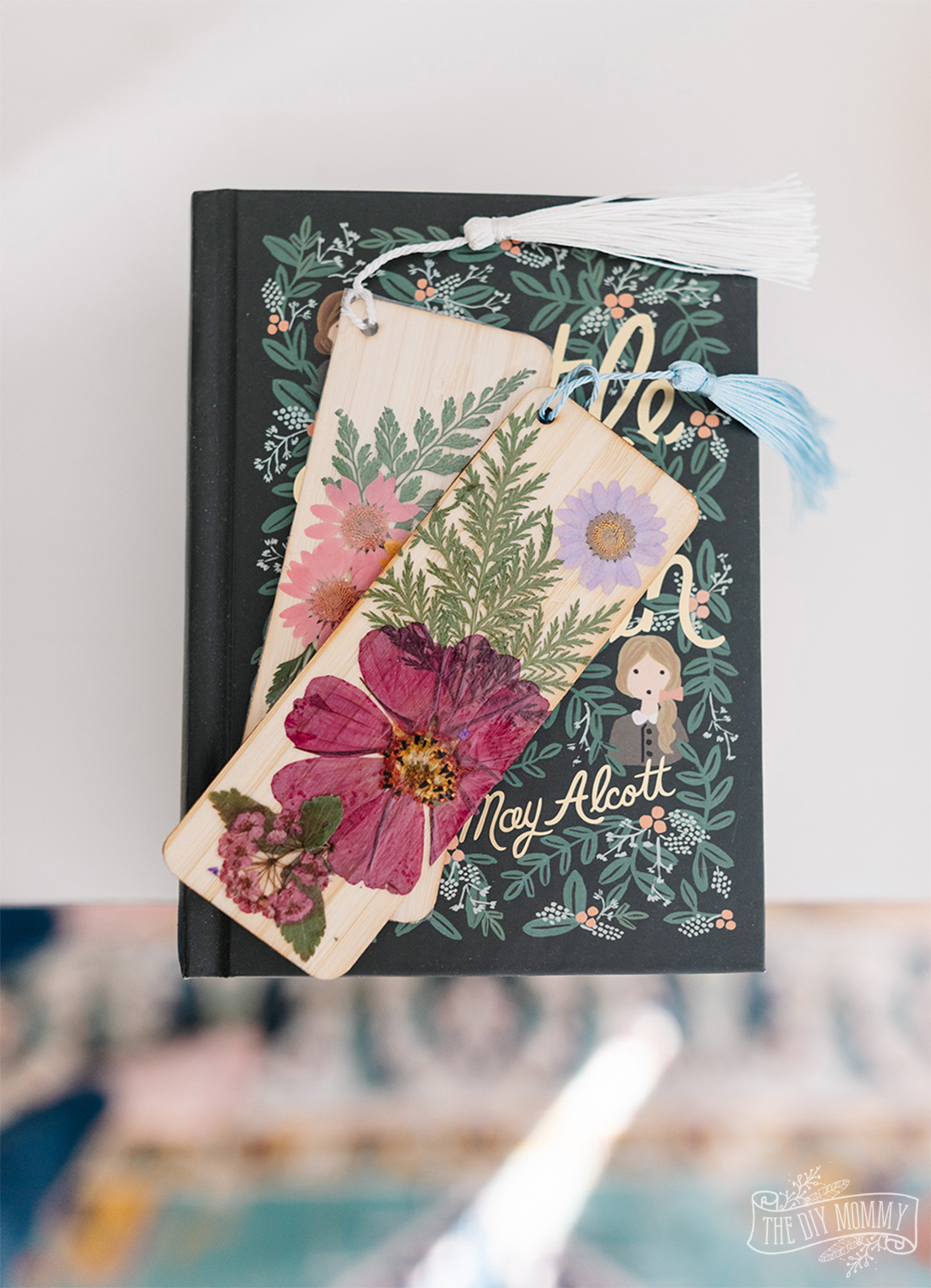 2 DIY Pressed Flower bookmarks displayed on a book. A perfect DIY Christmas gift idea for any teacher.