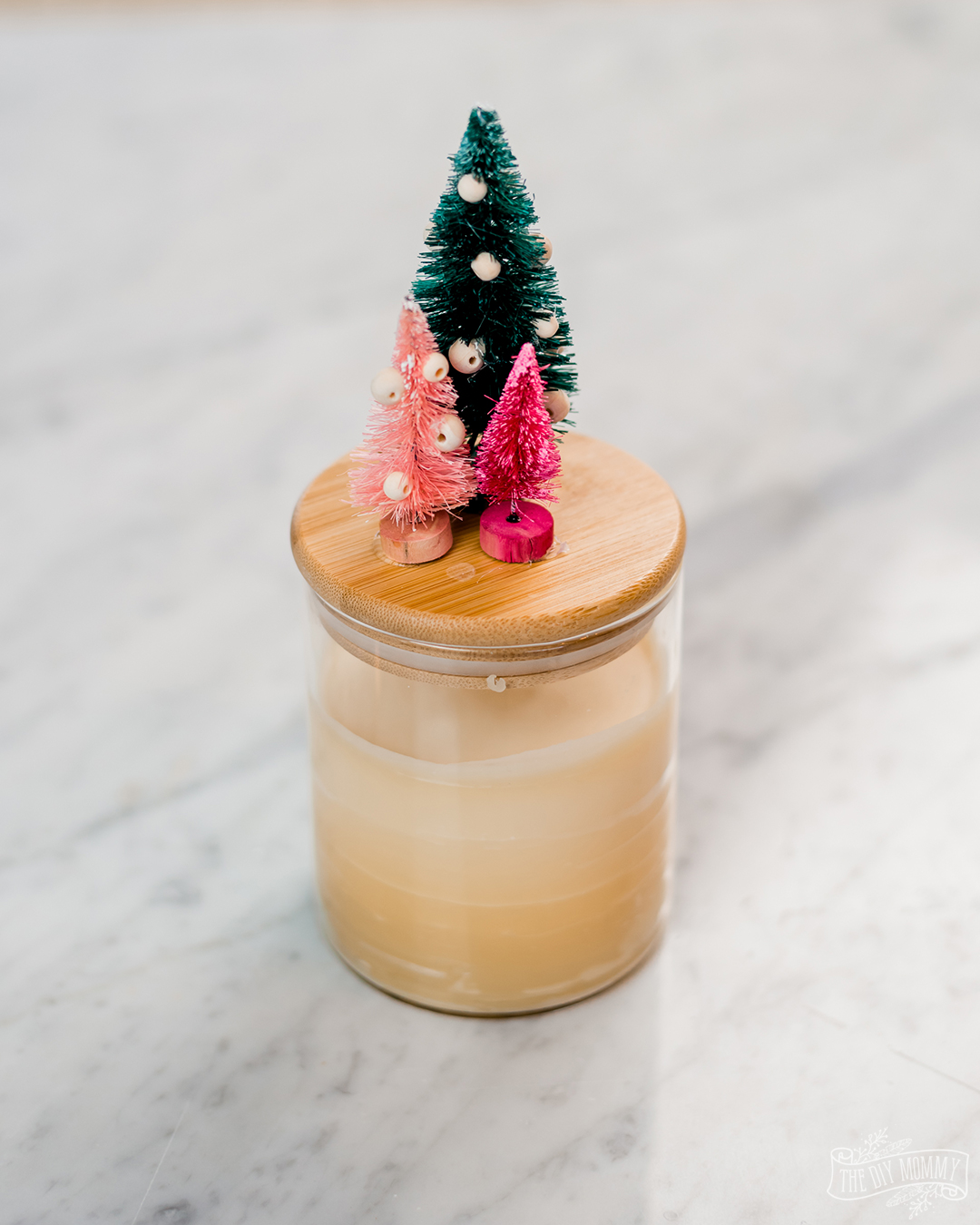 This is the cutest handmade gift! Make a DIY Christmas beeswax candle in a dollar store container and glue bottle brush trees to the lid.