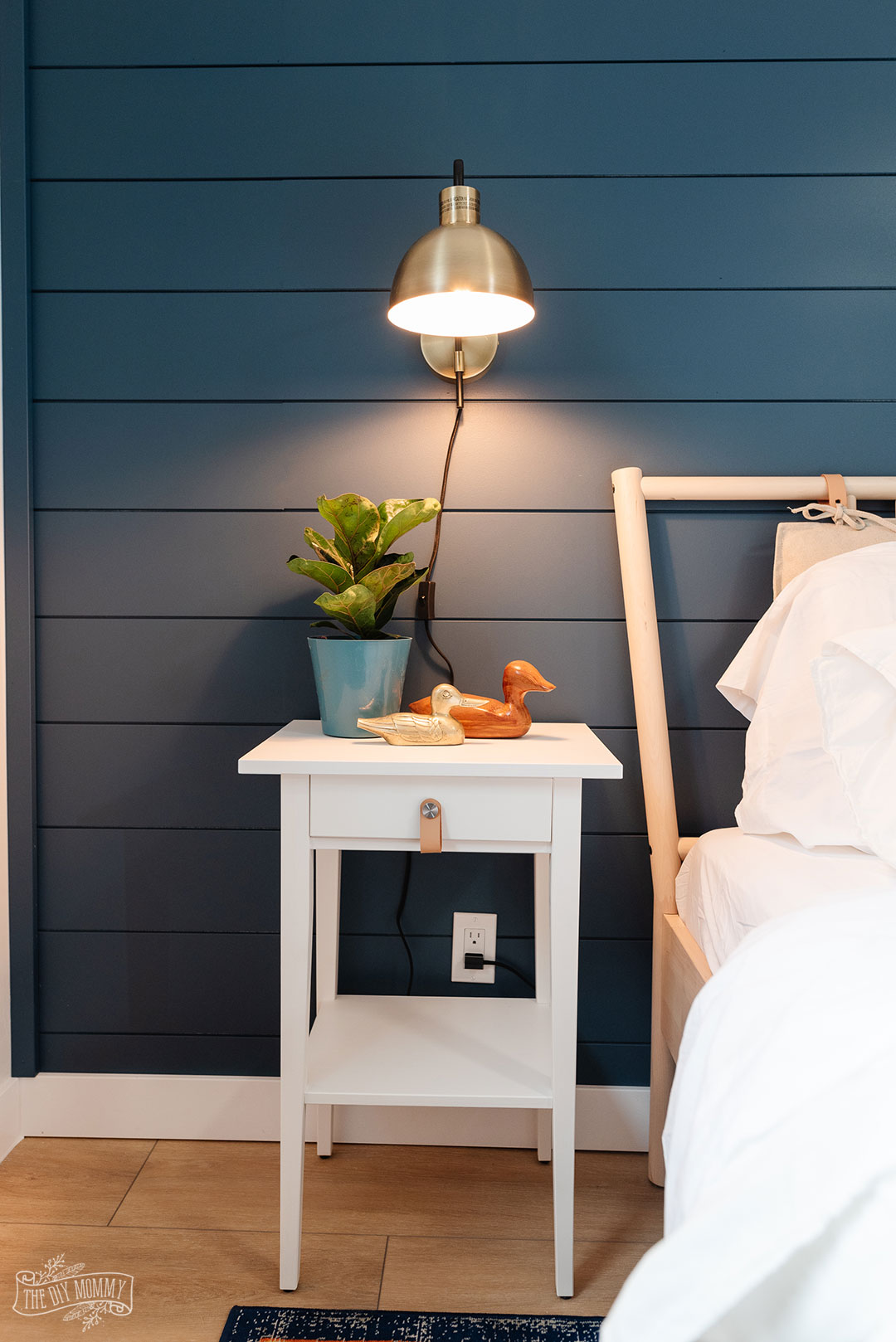 Relooking moderne d'une chambre côtière avec un mur bleu profond, un sol en planches de vinyle, des meubles IKEA et des accents dorés