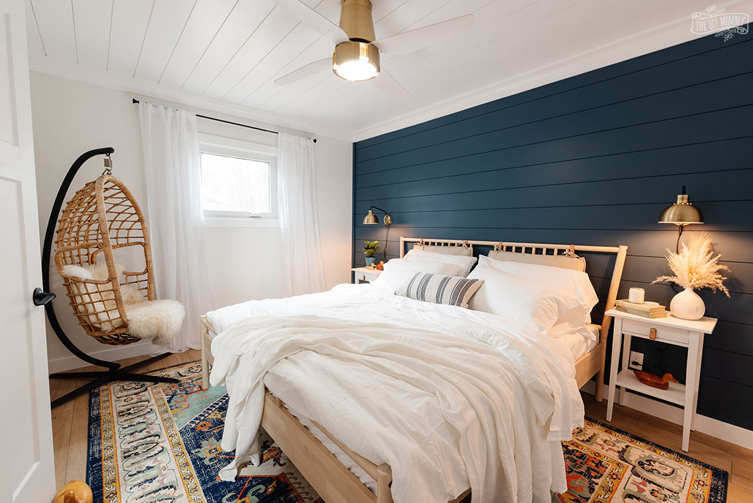 Relooking moderne d'une chambre côtière avec un mur bleu profond, un sol en planches de vinyle, des meubles IKEA et des accents dorés