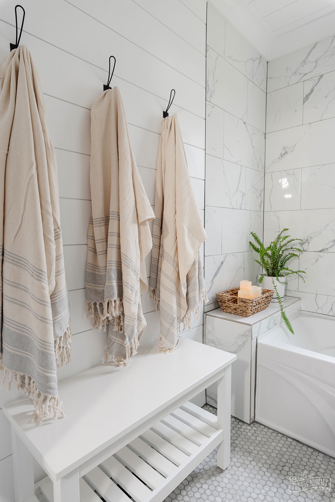 Modern coastal inspired bathroom renovation with marble tile, shiplap, gold and black accessories, clear shower door, blue and white colors & rattan accents