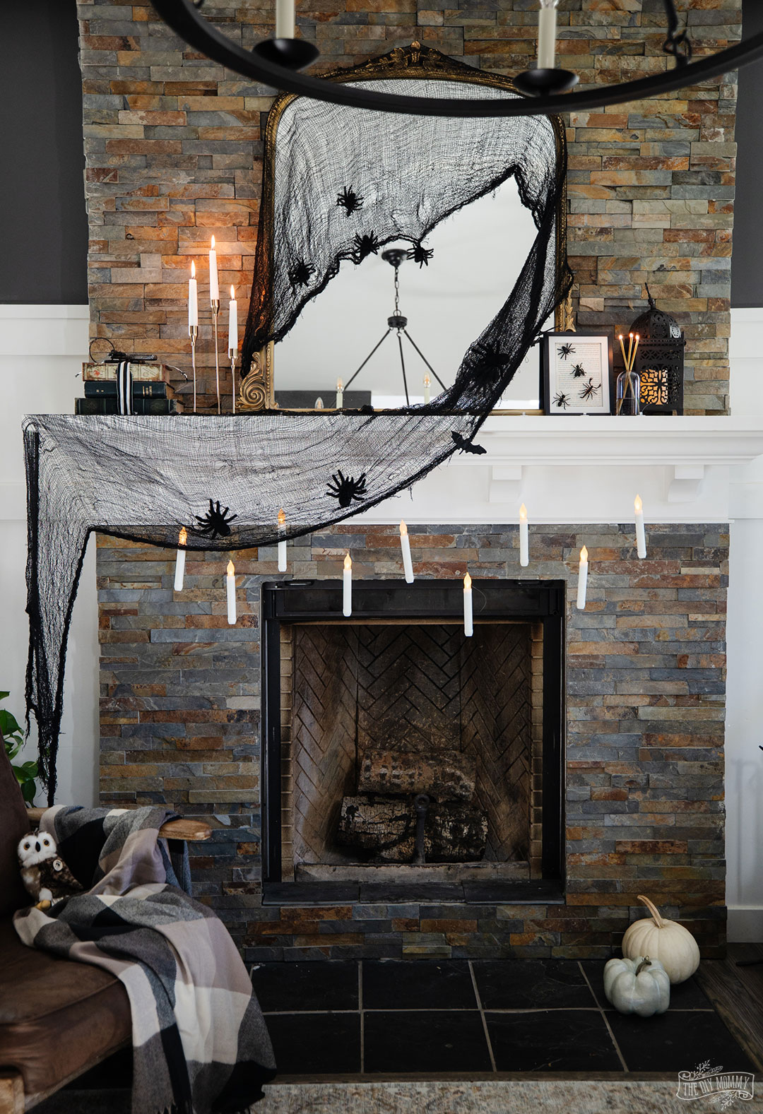 Harry Potter inspired mantle decorated with a mirror draped in black fabric, spiders, candlesticks and some floating candles. 