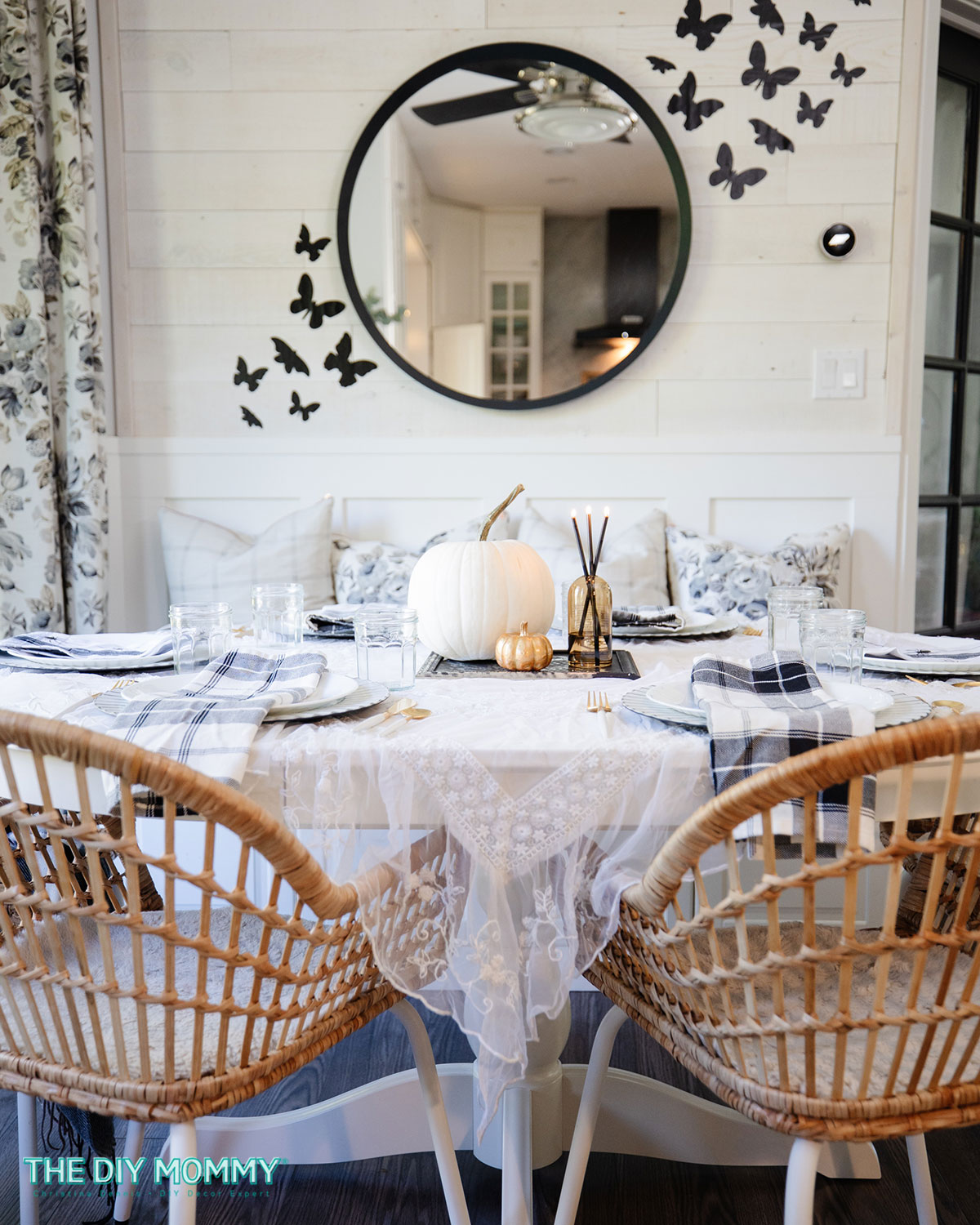 Halloween tablescape consisting of a faux white pumpkin, smaller gold pumpkin and candles.  Also featured are black and white table napkins and a white lace tablecloth