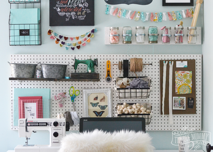 A beautiful, colorful craft room office wall with pegboard for storage, baskets, #DIY garlands, art and hanging mason jar storage.