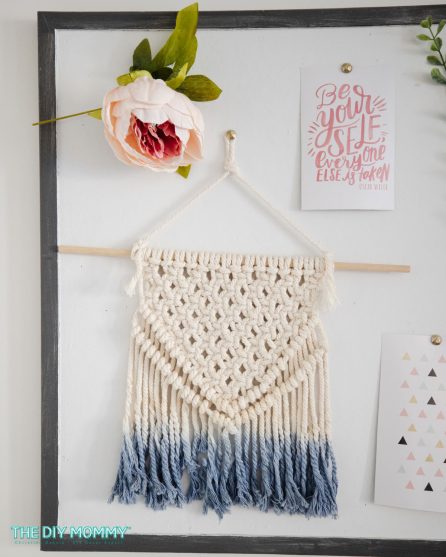 A DIY macrame wall hanging is attached to a bulletin board.