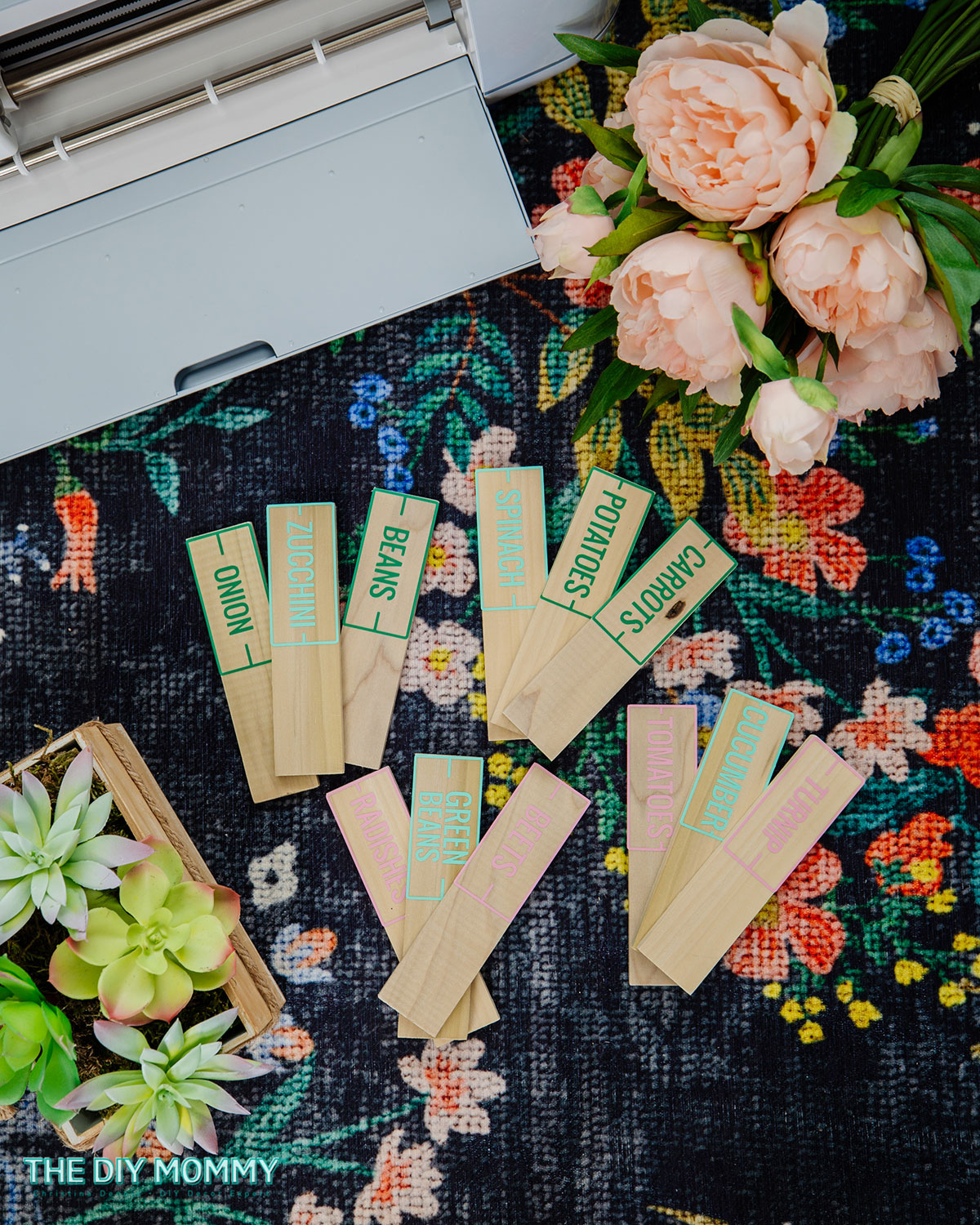 Seed markers are created using small wooden stakes and vinyl. These gardening gifts can easily be personalized with your favorite vegetable seeds.