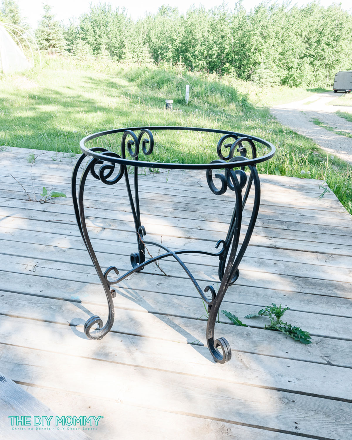 An old patio table with a wrought iron base and glass top