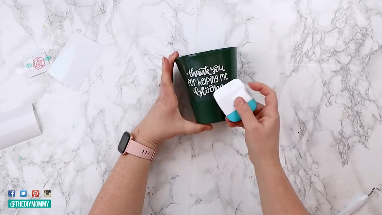A white vinyl decal, "thank you for helping me bloom" is applied to a green cup. 